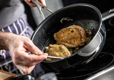 Person, die Hühnchen in einer großen Bratpfanne kocht