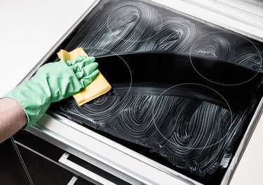 Person, die ein Induktionskochfeld reinigt